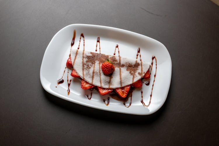 A Crepe With Strawberry Filling On A Ceramic Plate