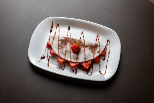 Free Appetizing crepe with strawberries and chocolate drizzle, perfect dessert shot. Stock Photo