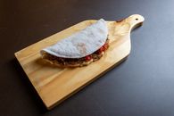 A flavorful tapioca wrap filled with ingredients displayed on a wooden board.