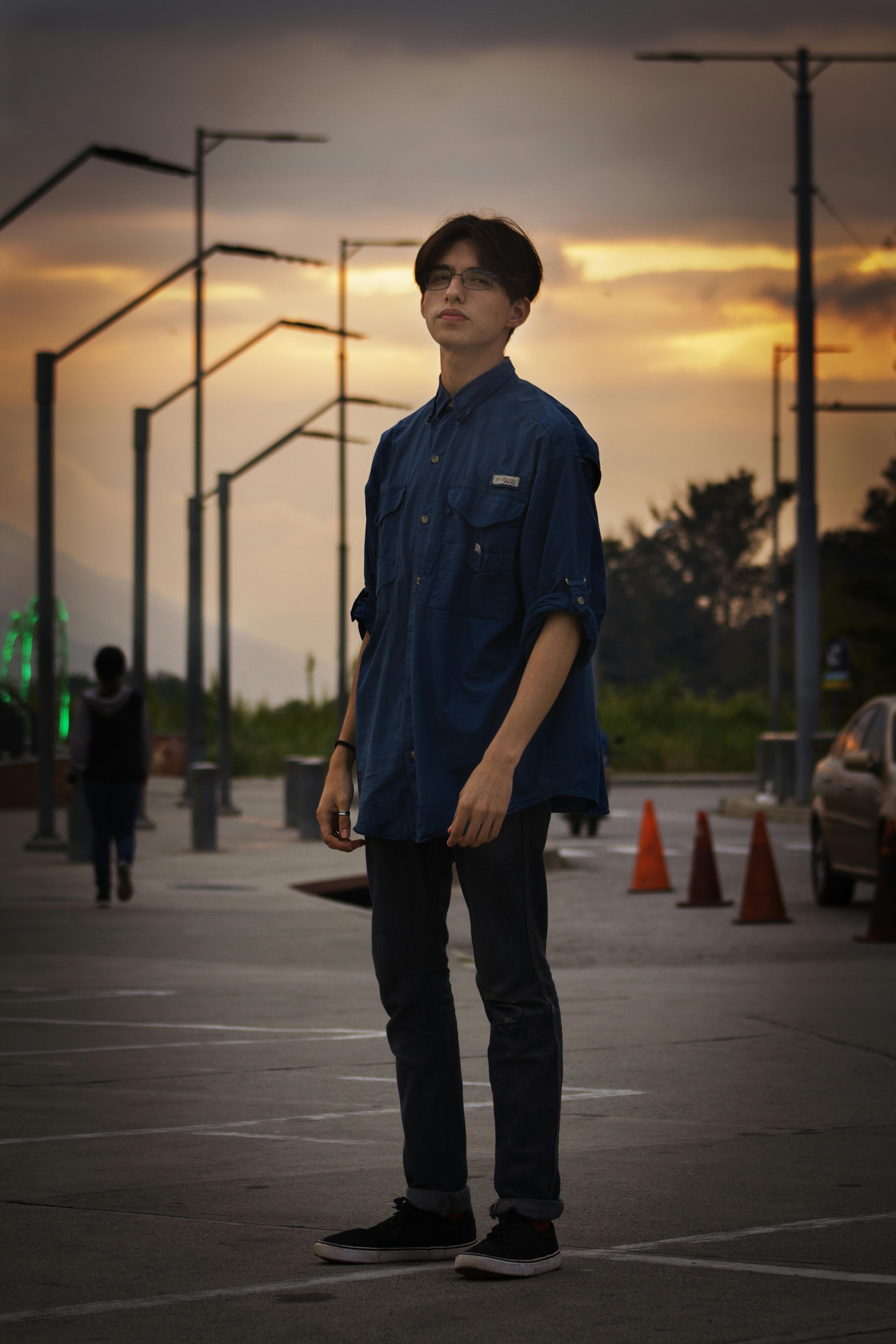 man in blue button up shirt standing on sidewalk