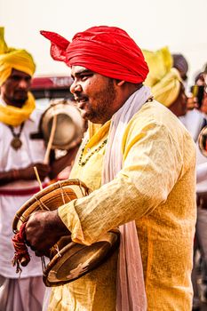 Musicians in traditional attire perform with drums at an Indian festival.