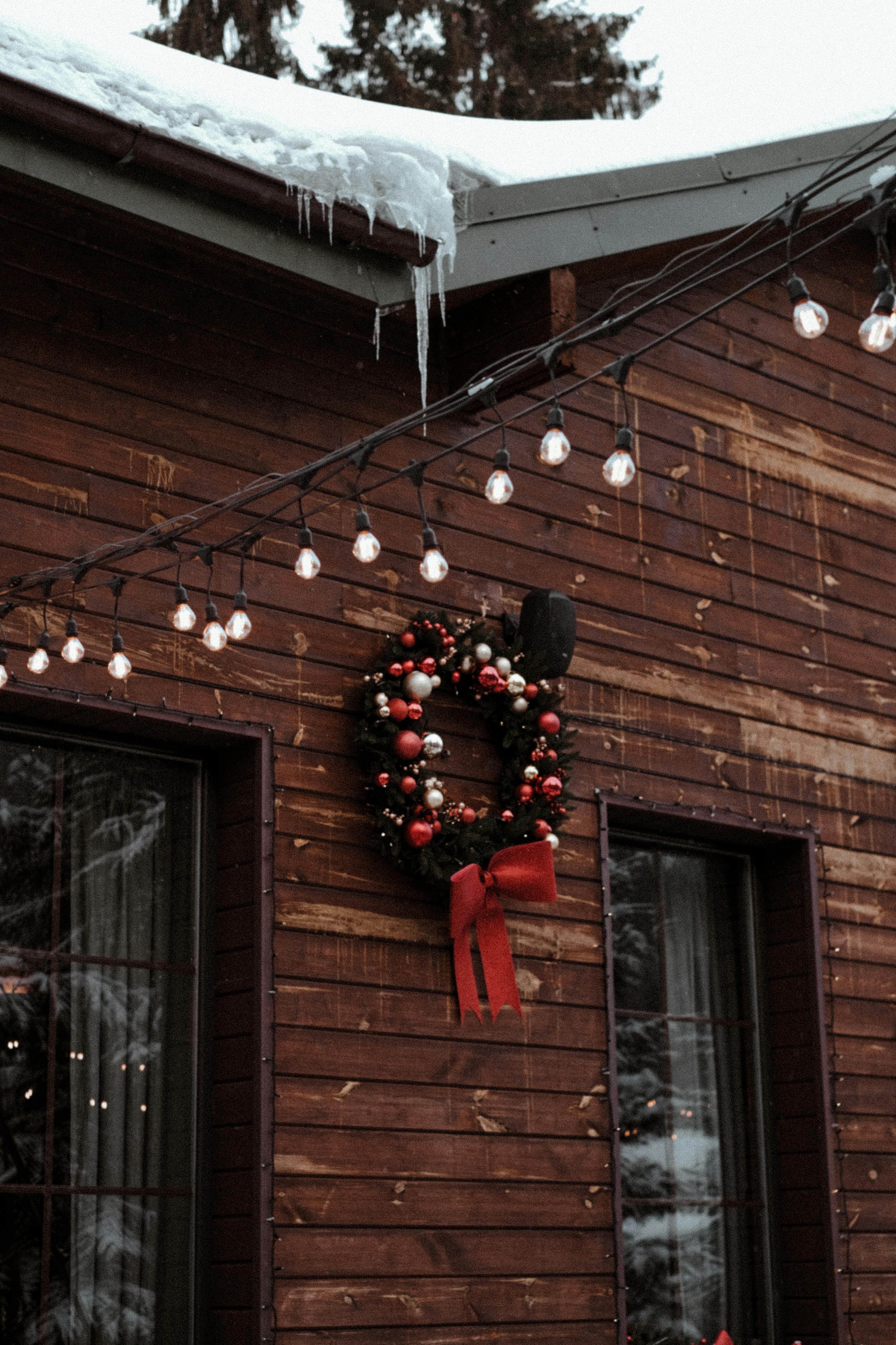 A festive Christmas wreath decorates a snow-covered wooden house in Bukovel, Ukraine, creating a cozy winter atmosphere.
