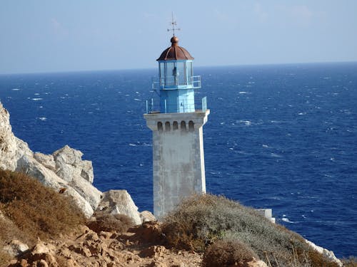 Free White and Blue Concrete Lighthouse Near Body of Water Stock Photo