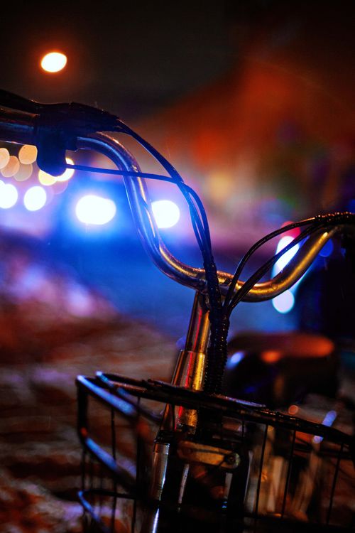 Free Close-up of a bicycle handlebar at night with colorful bokeh lights in the background. Stock Photo