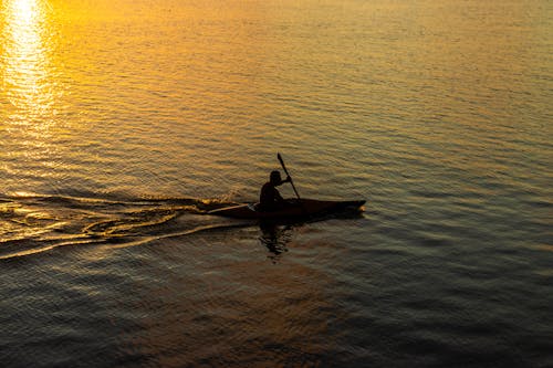 Man Riding a Boat on Body of Water