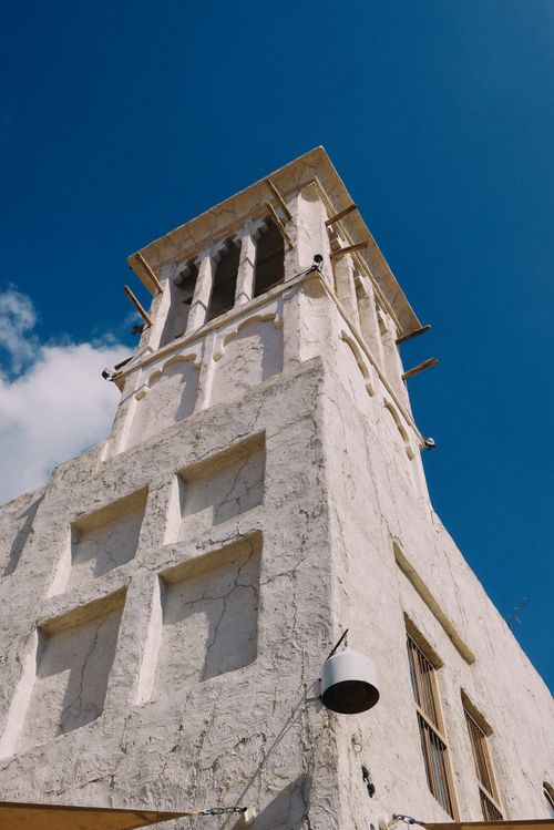 Free A traditional wind tower in Dubai stands tall under a clear blue sky, showcasing architectural heritage. Stock Photo