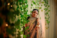 Woman in Brown and Red Floral Hijab Standing Near Green Plants