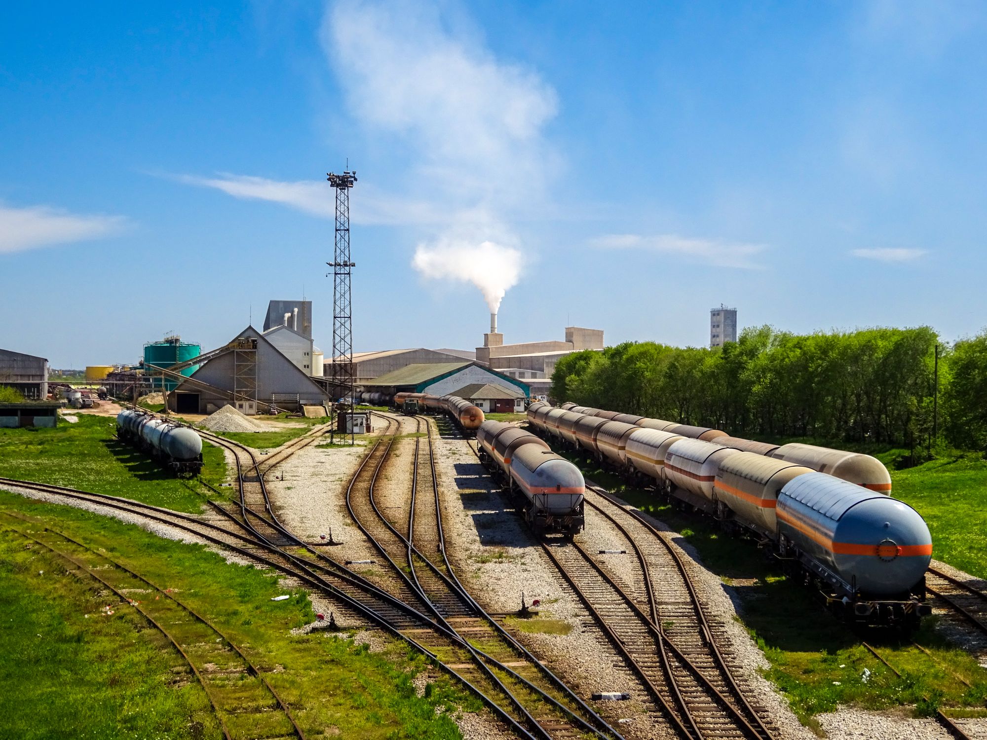A vibrant industrial railway yard in Šabac, Serbia showcasing multiple train cars and smoking stacks.