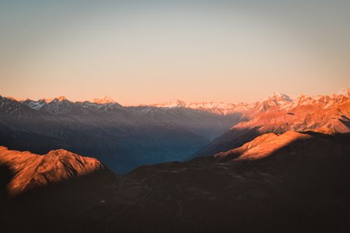 Free Peaceful sunrise casting warm glow over snow-capped mountain range. Stock Photo
