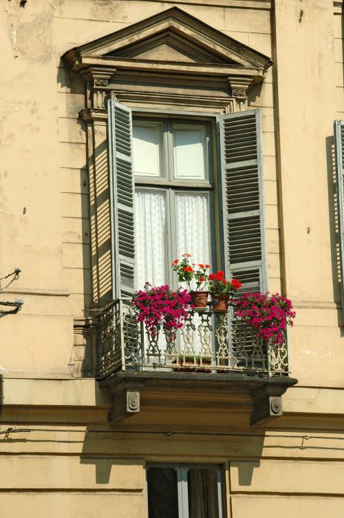 Free Lovely antique building facade featuring a picturesque balcony with vibrant flowers. Stock Photo