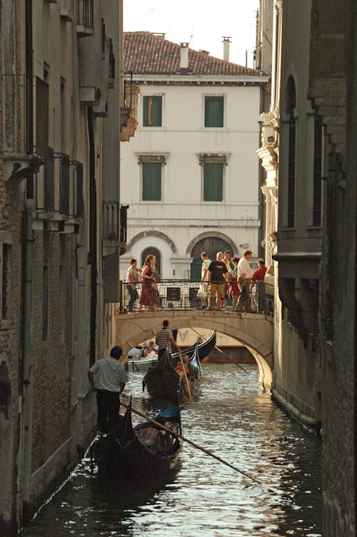 People Riding on Gondolas Near a Bridge