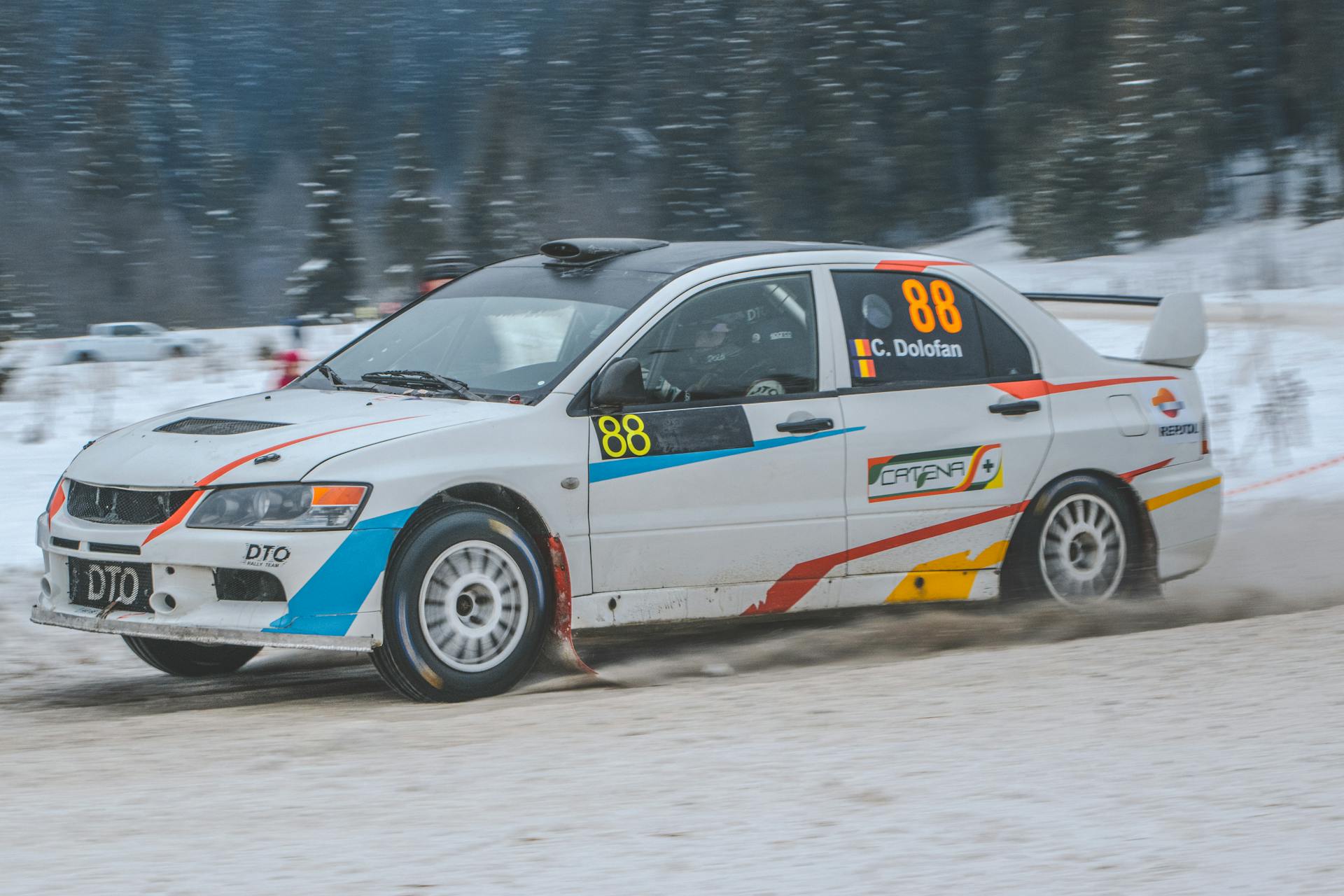 Experience the thrill of winter car racing as a Mitsubishi Lancer races across snowy landscapes in Comandău, Romania.