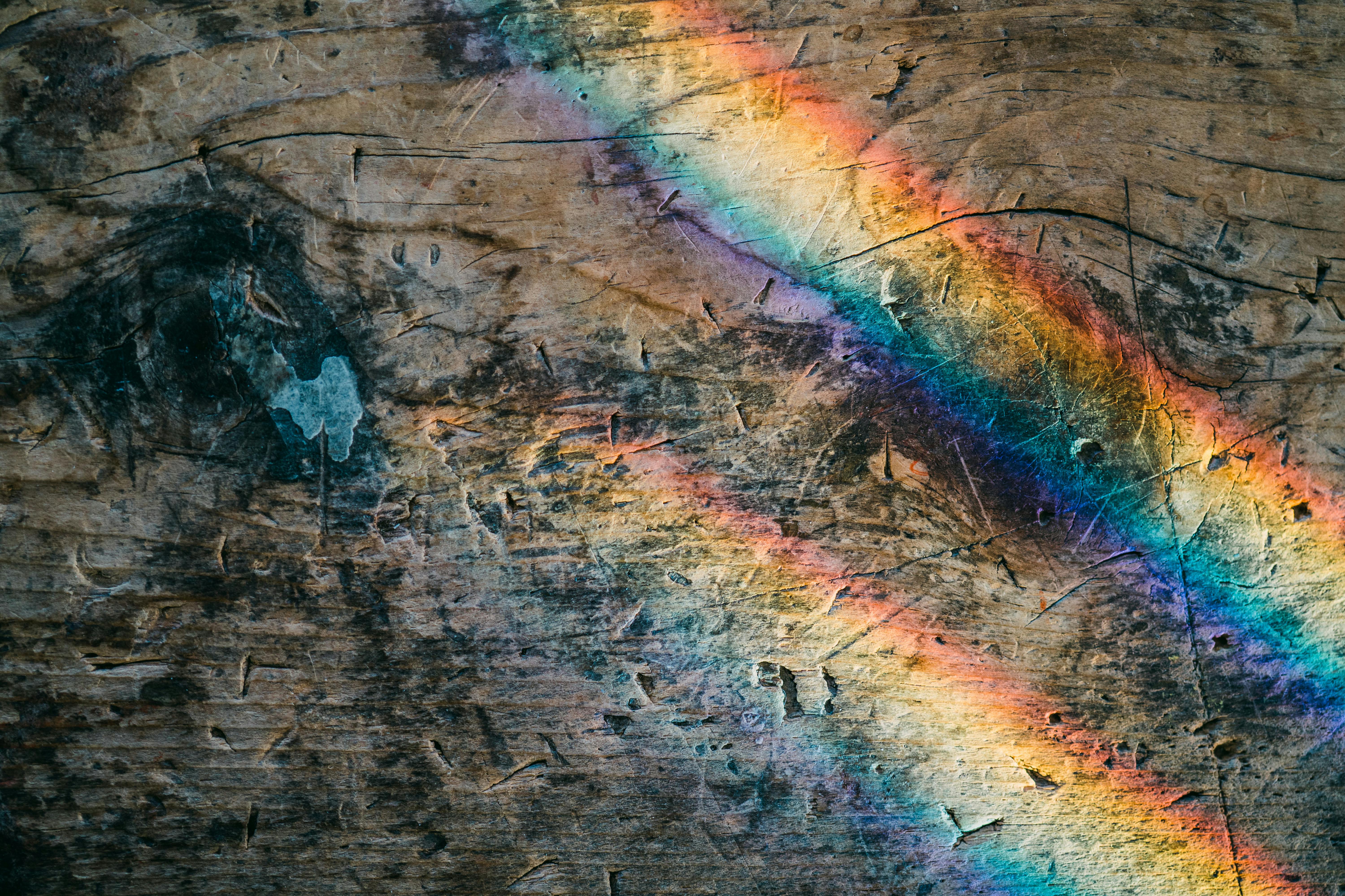 Vibrant rainbow reflections create a fascinating pattern on an aged wooden surface.