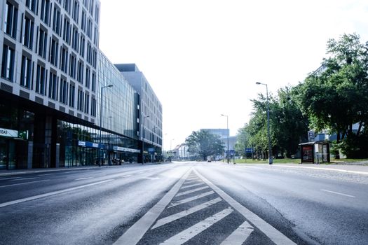 Wide-angle view of a modern urban street in Wrocław, Poland, with high-rise buildings and greenery.