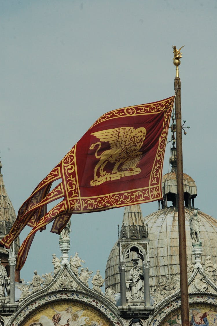 Venetian Flag Swaying By The Wind Near Basilica San Marco 