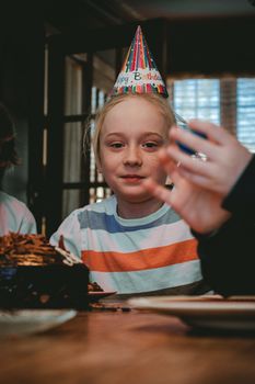 A cheerful child wearing a birthday hat indoors. Perfect for festive themes.