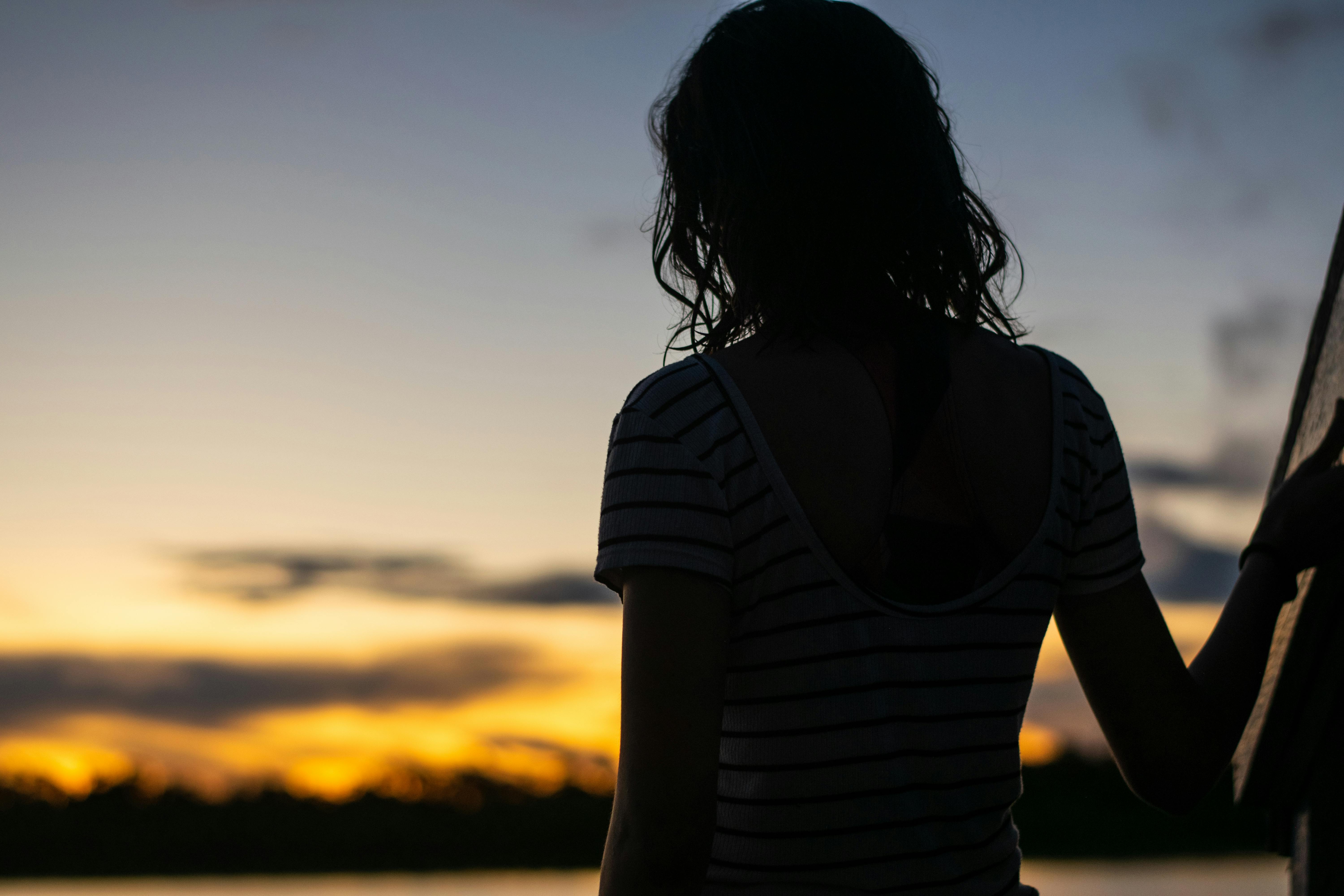 Silhouette of a woman viewing the sunset in Iquitos, Peru, offering a serene and reflective scene.