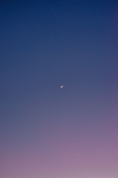 Free A serene view of a crescent moon against a twilight gradient sky, evoking tranquility. Stock Photo