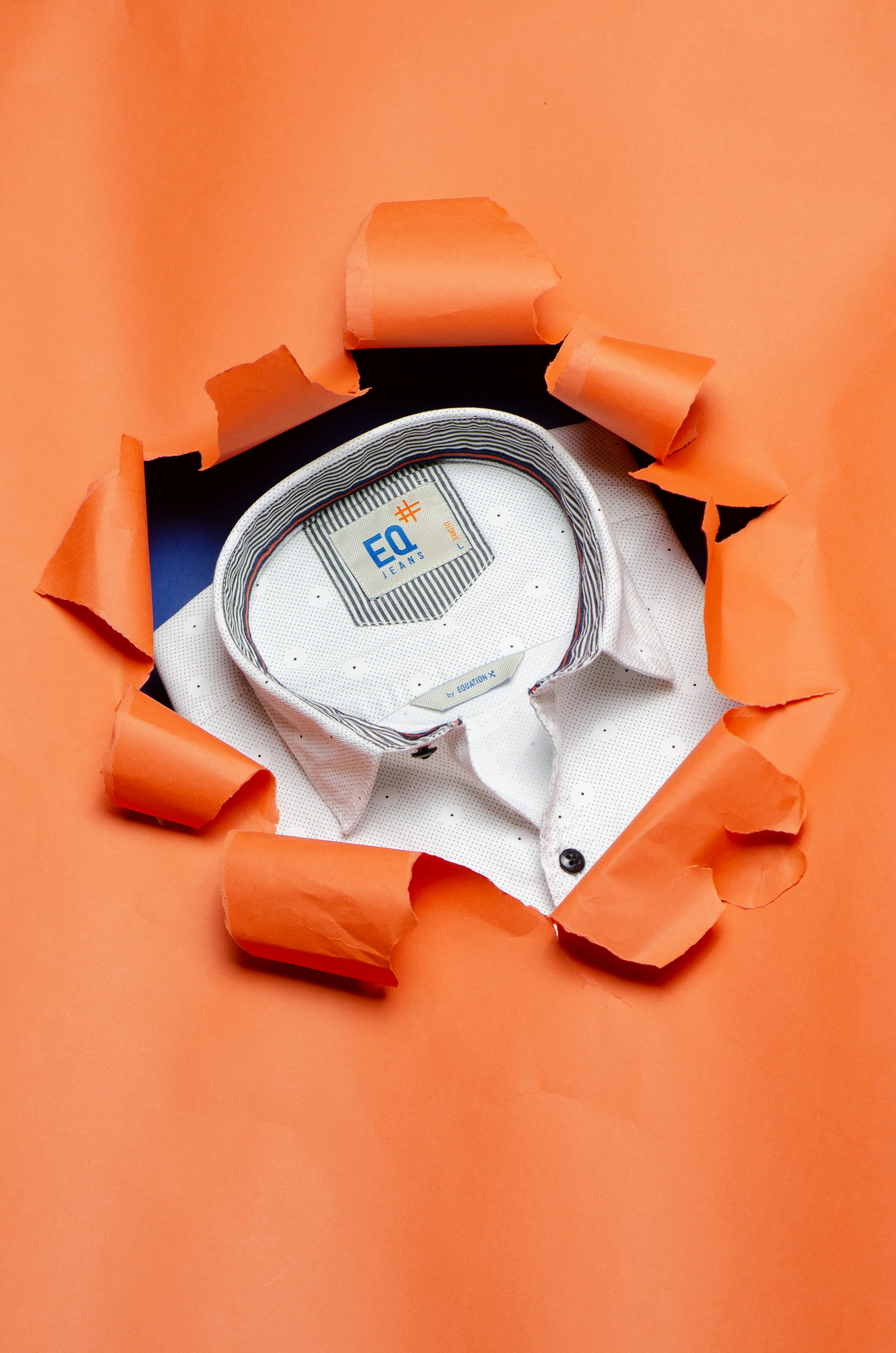 White shirt with a polka dot pattern, seen through torn orange paper.