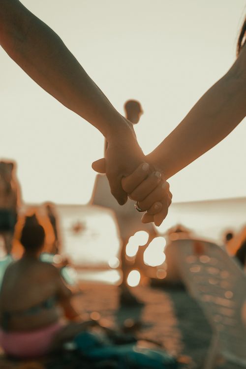 Free A close-up of a couple holding hands on a sunny beach day, capturing a romantic moment. Stock Photo