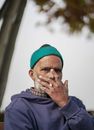 An Elderly Man in Knitted Cap Smoking Cigarette