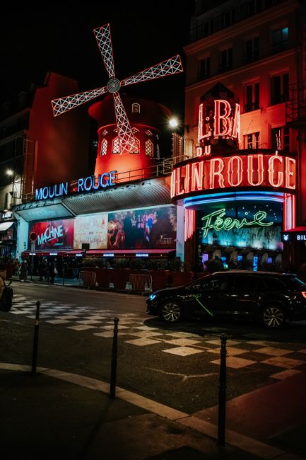 Vibrant night scene of the famous Moulin Rouge in Paris with neon lights and bustling atmosphere.