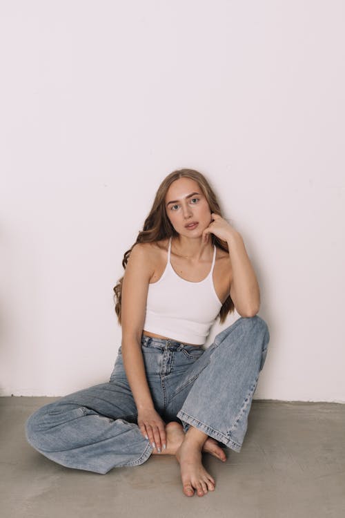 A Woman in White Tank Top and Denim Jeans Sitting on the Floor