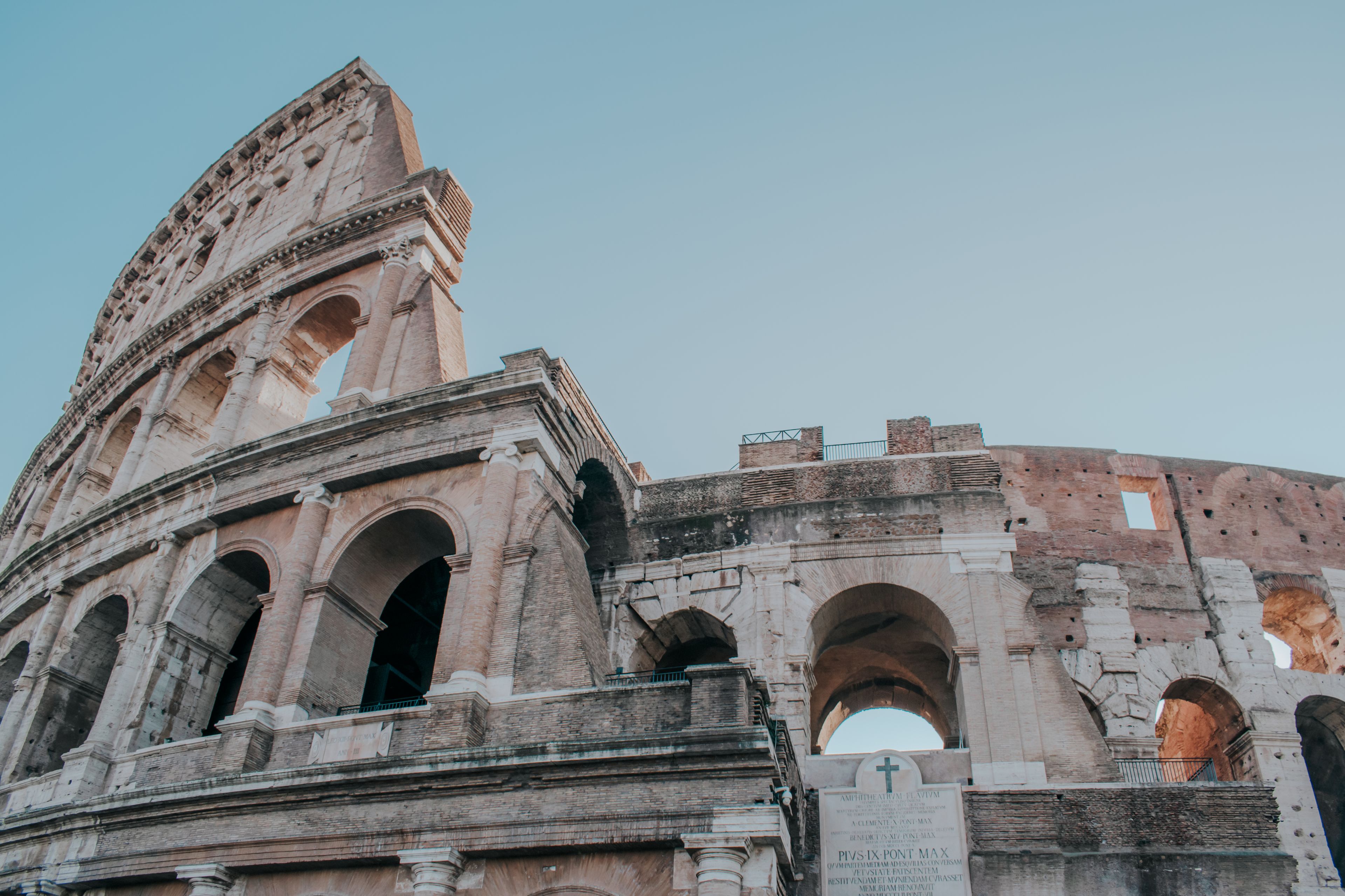 Low angle view of the ancient Colosseum in Rome against a blue sky.