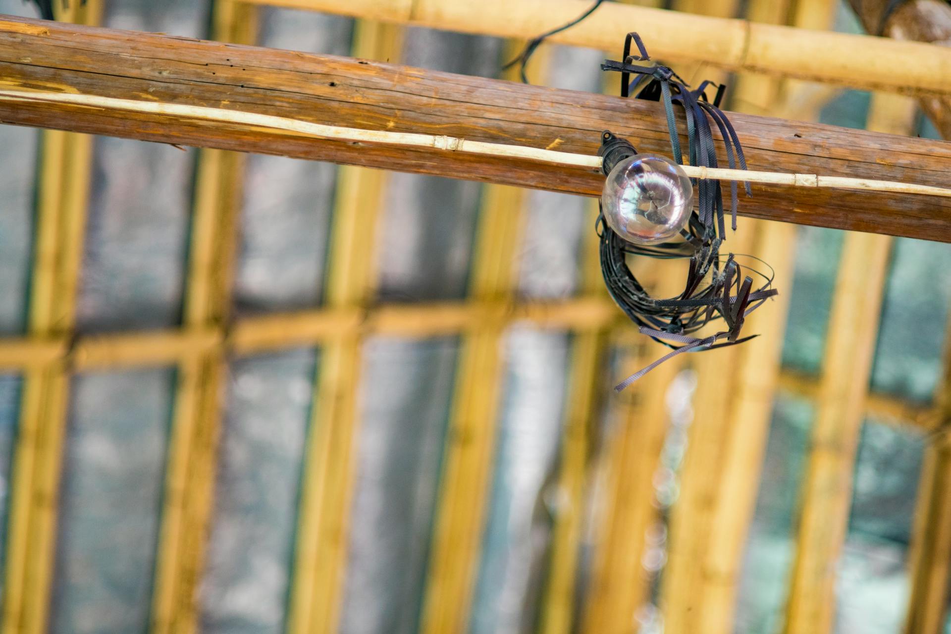 Rustic ceiling structure with an exposed bulb hanging from wooden beams.