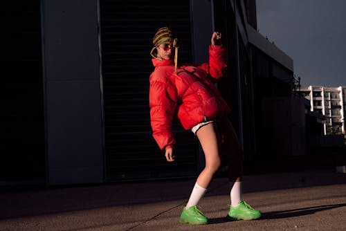 Woman in a Red Jacket and Shorts Wearing Green Rubber Shoes
