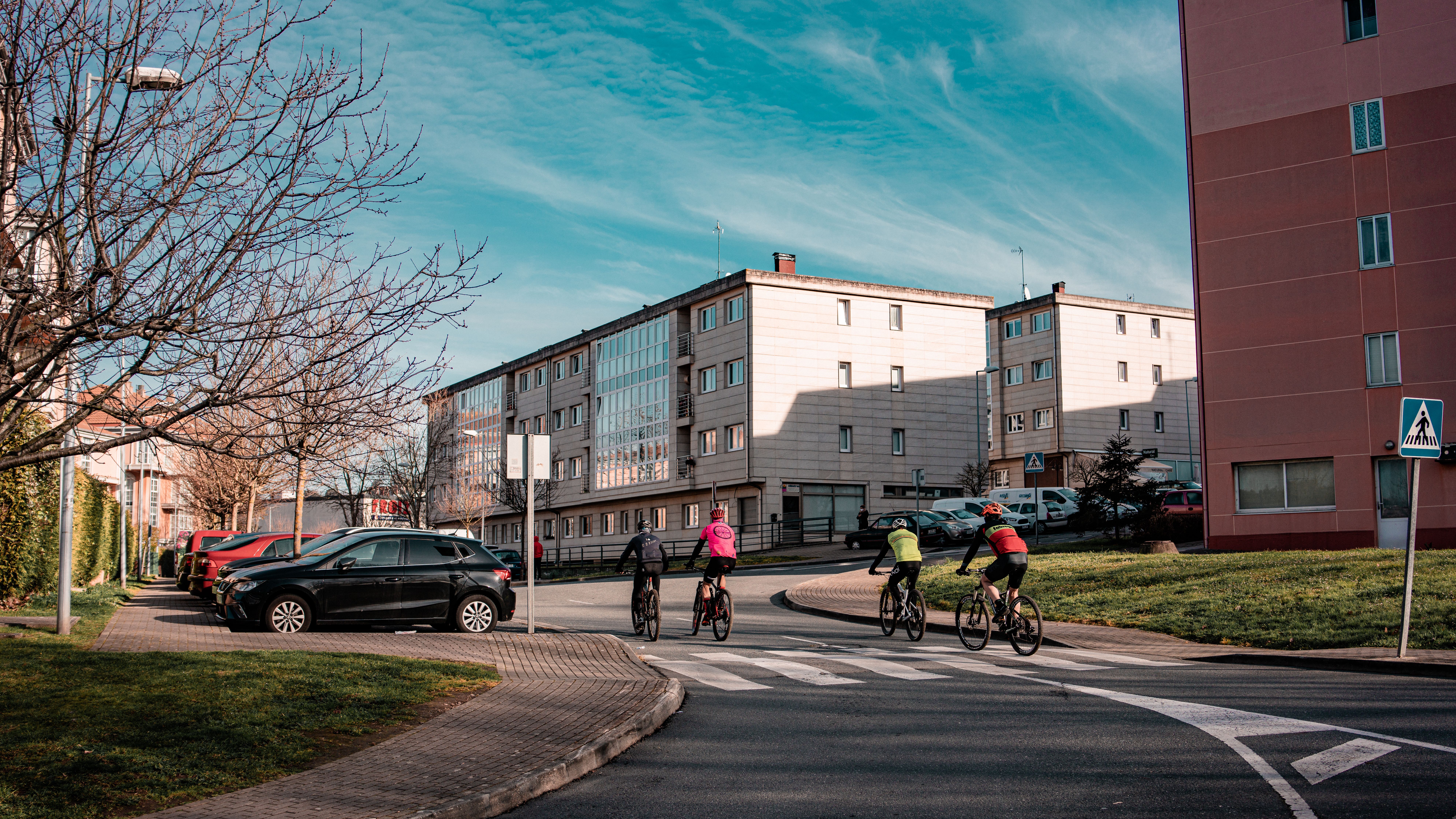 Cyclists biking through urban streets in O Seixo, Galicia, Spain on a sunny day