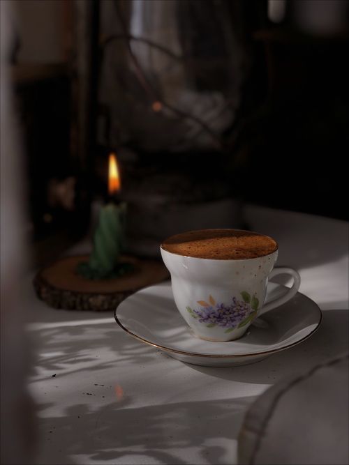Free A warm and cozy coffee cup beside a candle, creating a peaceful and intimate atmosphere. Stock Photo