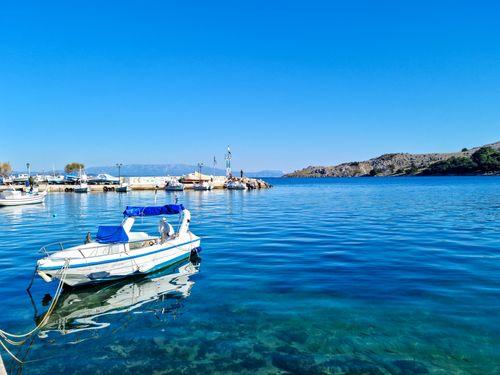 Free Peaceful harbor scene in Greece with boats and clear blue water under a bright sky. Stock Photo