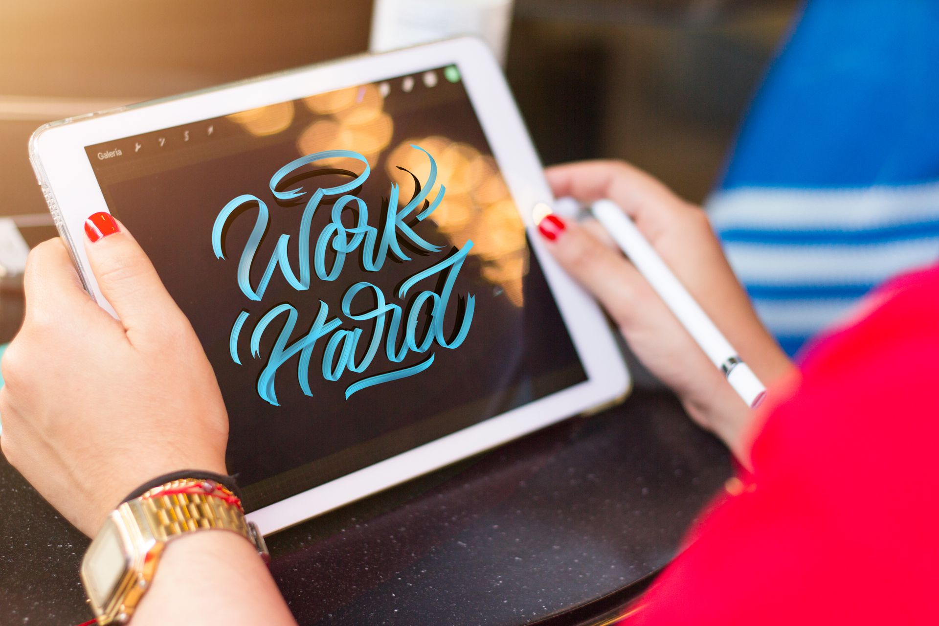 Woman practicing digital calligraphy on a tablet in a Bogotá cafe setting. Creative and modern art.