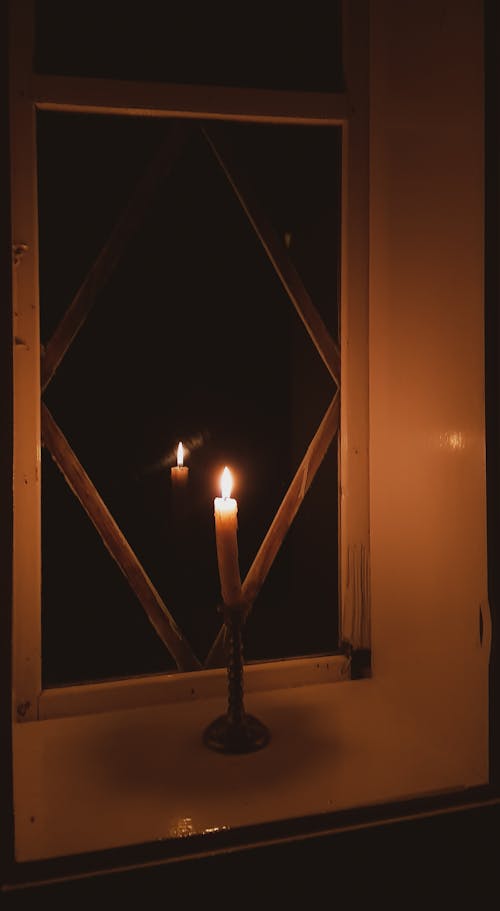 Lighted Candle Near a Glass Window