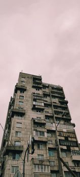 Low angle view of a brutalist apartment building against a pink sky.
