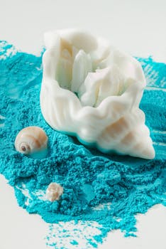 Artistic white conch and seashells on vibrant blue powder, a creative composition.