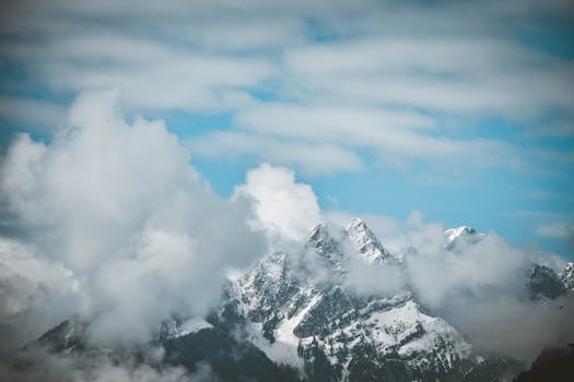 Breathtaking view of snow-covered mountains shrouded in clouds in Tirol, Austria.