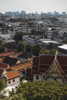 Aerial view of Bangkok with traditional temple rooftops and a modern skyline.