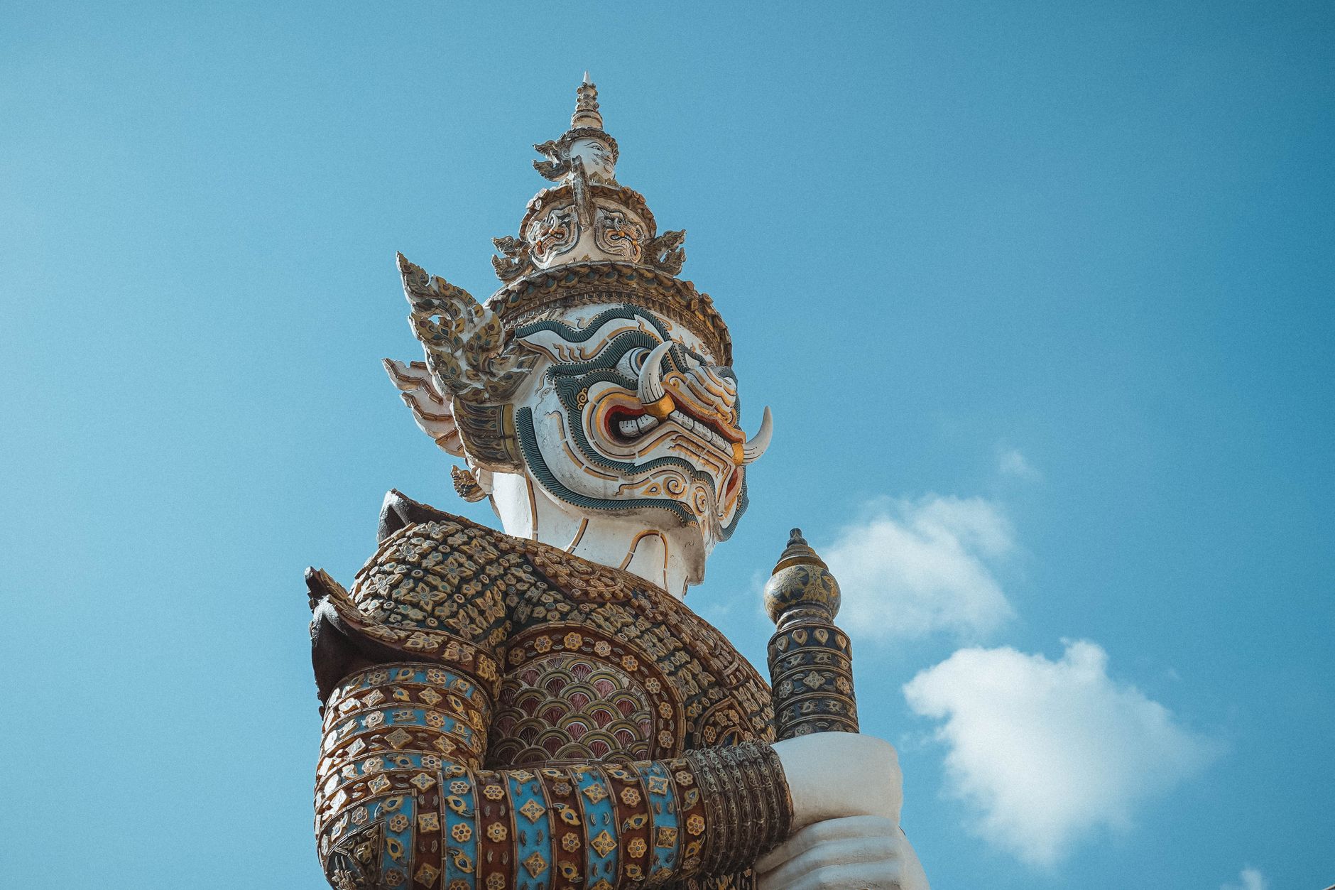 Low angle view of an ornate Yaksha statue against a clear blue sky in Bangkok, Thailand.
