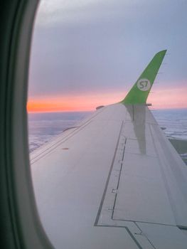 Aerial view of an airplane wing during a captivating sunset flight, looking over the horizon.