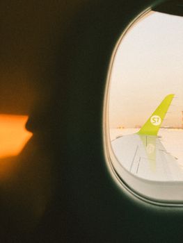 View of airplane wing through cabin window at sunrise, highlighting travel experience.