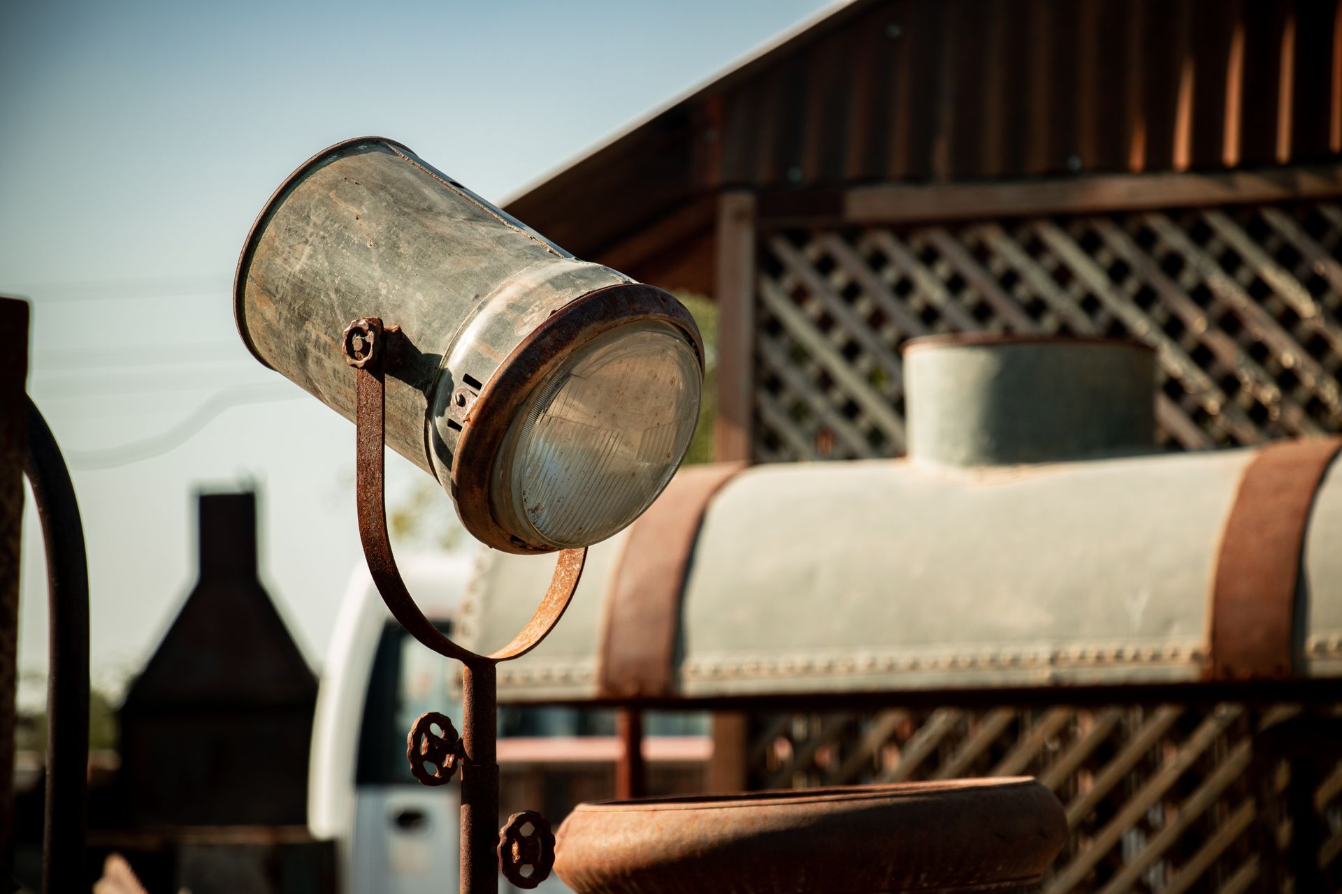 Close-up of a vintage rusty nautical lamp on an old structure with blurred background outdoors.
