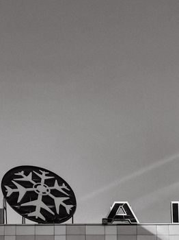 Minimalist black and white image showing a snowflake sign on a building facade.