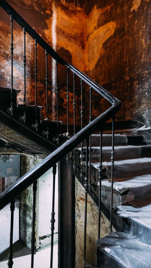 Free A moody, rustic staircase with iron railings in an abandoned building, showcasing decay and mystery. Stock Photo
