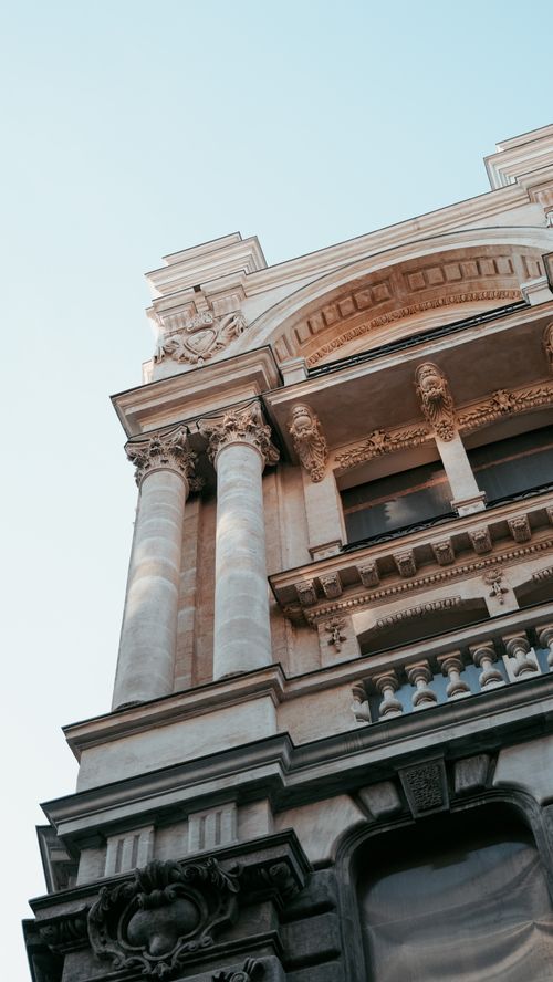 Free Low-angle view of a neoclassical building with ornate columns against a clear sky. Stock Photo