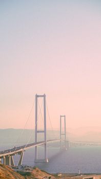 A picturesque view of the Osman Gazi Bridge enveloped in fog at sunset, creating a serene and scenic atmosphere.