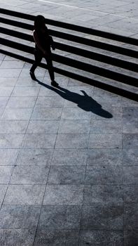 A striking high angle shot of a person casting a shadow while walking on city steps.
