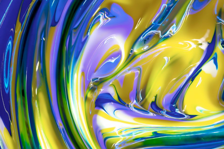 Dynamic swirl of blue, green, and yellow paints creating a vibrant abstract art piece.