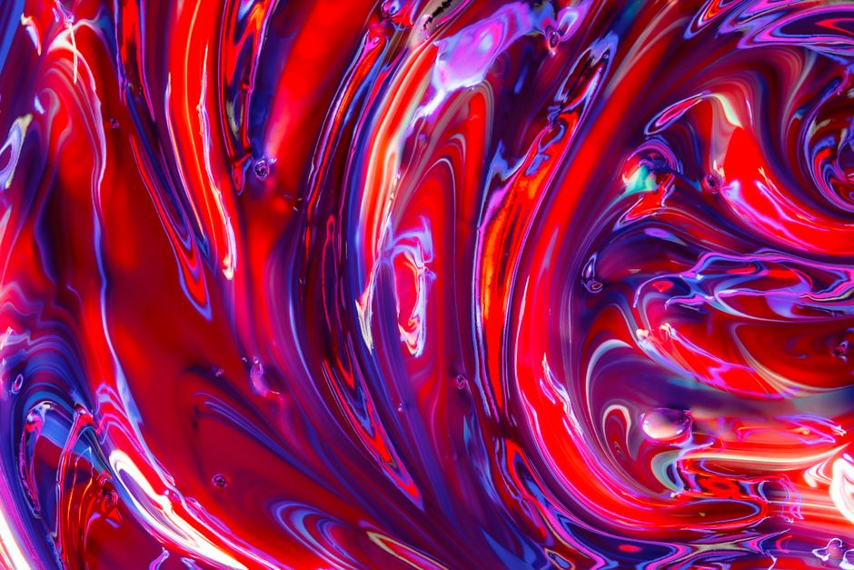 A vivid close-up of swirling red and blue acrylic paint, creating a mesmerizing abstract texture.